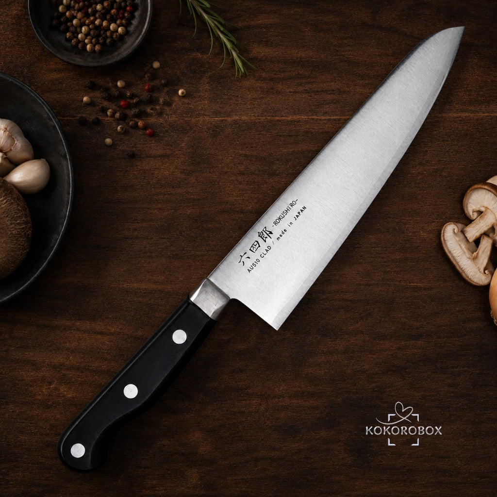 Cuchillo de chef Gyuto Kokorobox de 180mm en acero AUS-10 con mango ergonómico sobre tabla de madera con ingredientes